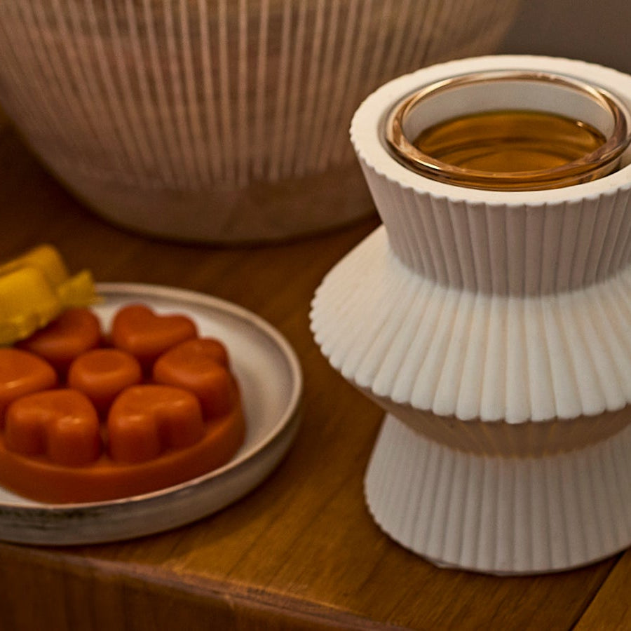 White wax melt warmer with wax melts on a side table