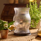 Modern Farmhouse Hurricane shown with house plants on a woven table runner.