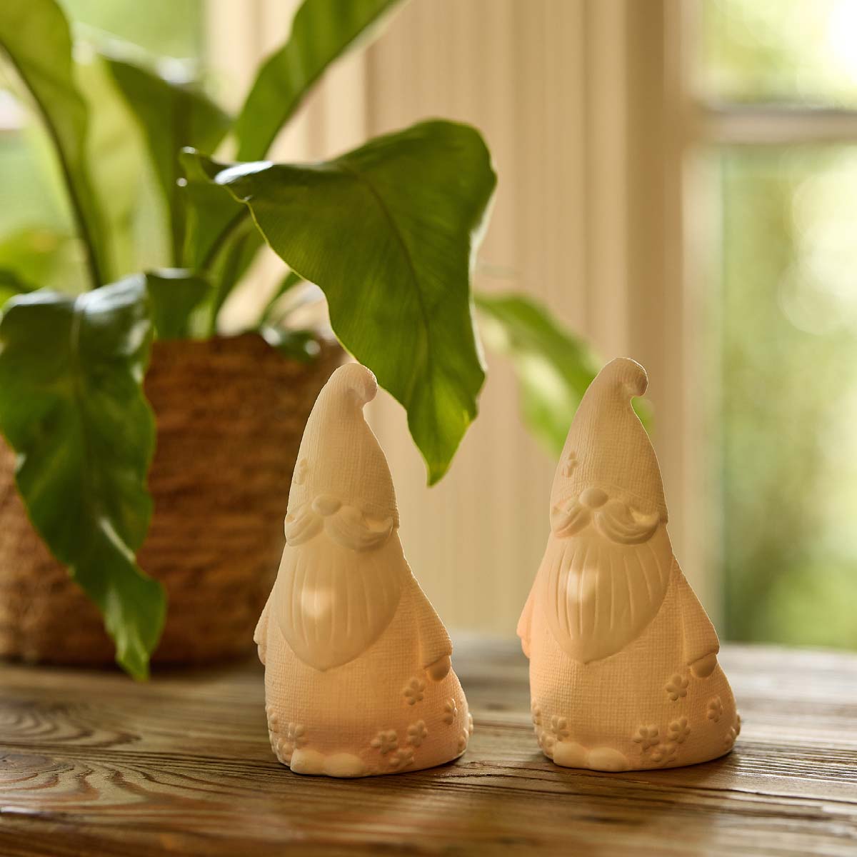Gnome 'n Garden Tealight Holder Pair on a wooden surface with a leafy plant next to them.