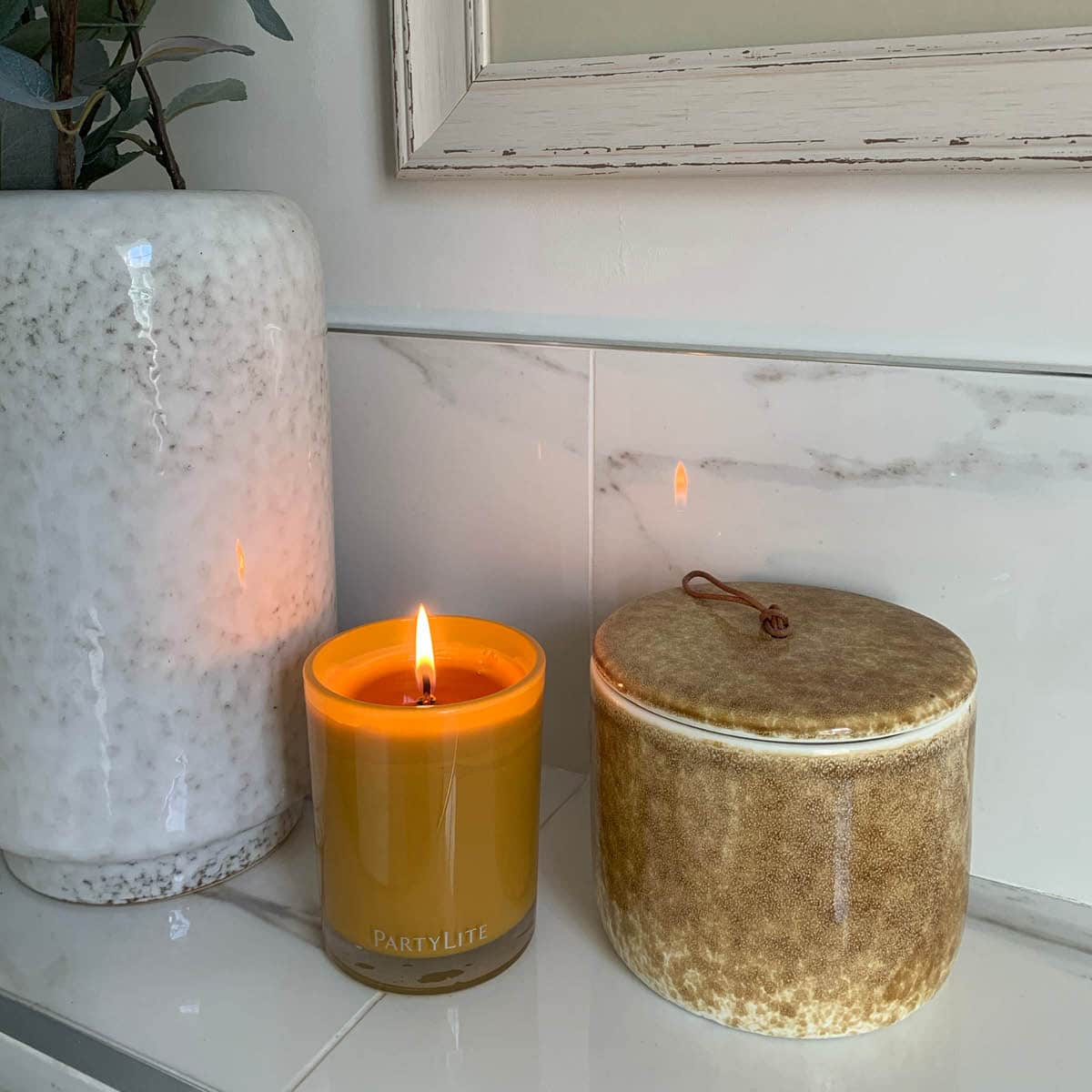 Whiskey & Oak Escential Jar Candle lit against a tiled background on a tiled surface.