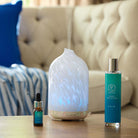 Calm Room Spray from the Mood Collection shown with the same fragrance oil with a diffuser next to them on a wooden surface.