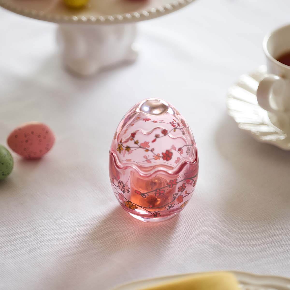 Flowered Egg Tealight Holder, pink glass on a white table top.