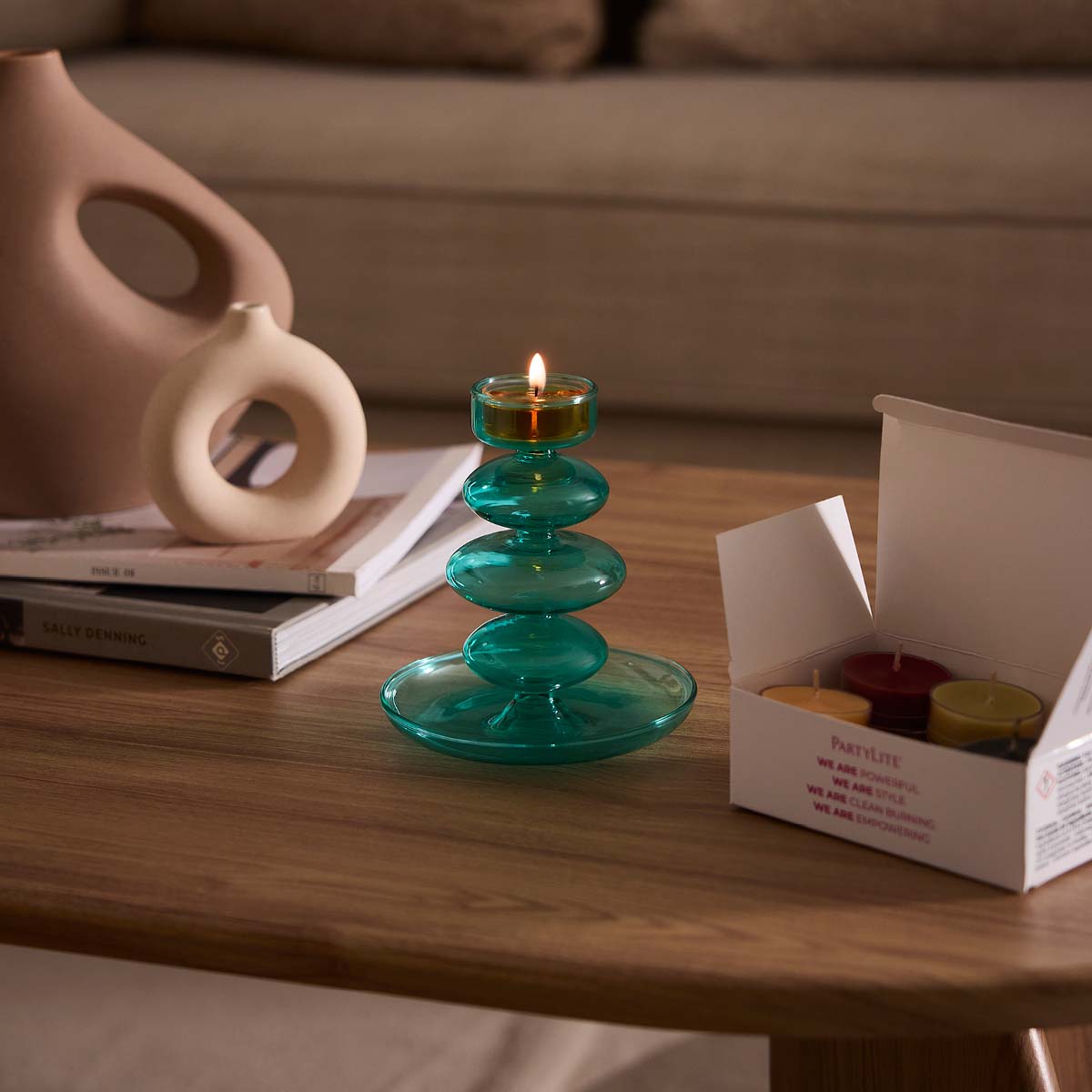 Blue Waves Tealight Holder with a lit tealight and a open box of tealights on a wooden surface.