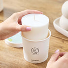 Iced Snowberries Wax refill shown being removed from it's container by a lady hands on a wooden surface.