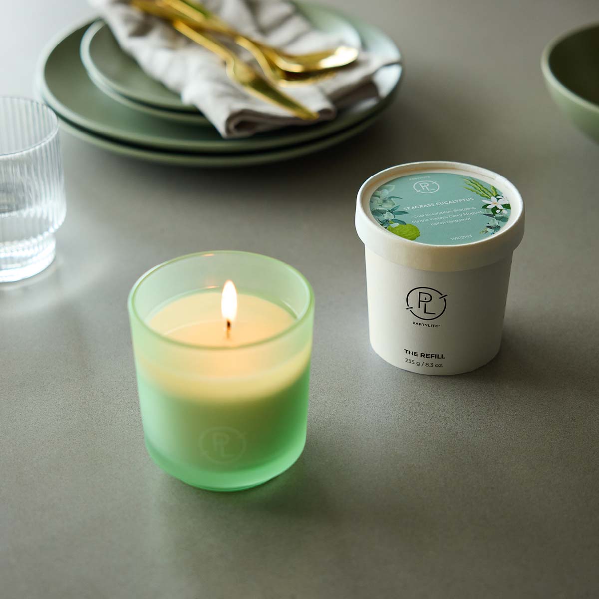 Seagrass Eucalyptus Refillable Wax shown with the Seagrass Eucalyptus Refill jar on a table top with plates and glasses in the background.