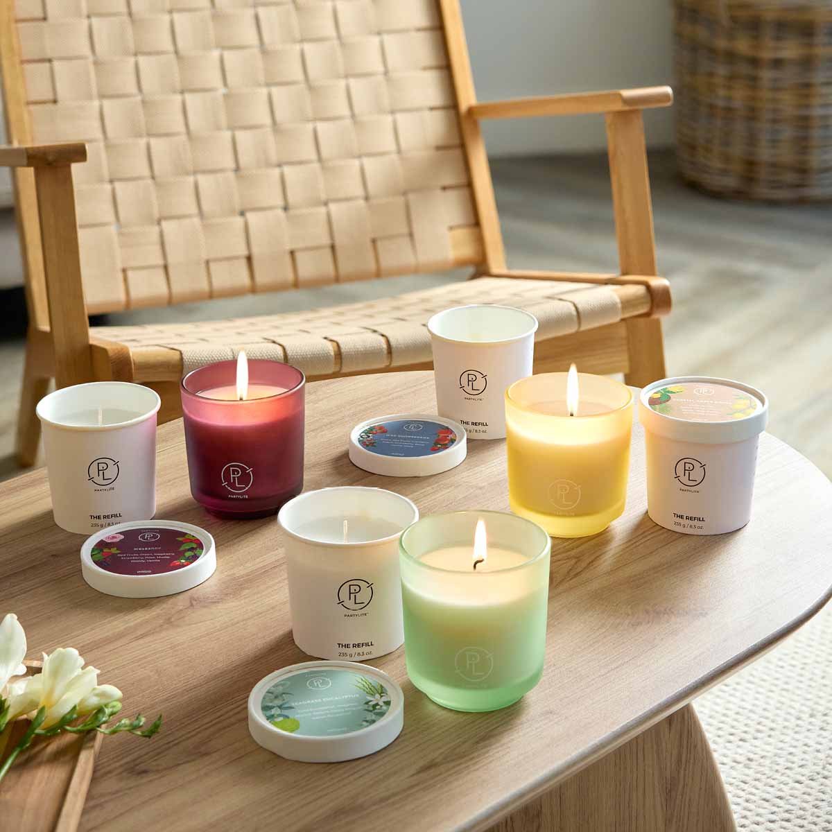 Assortment of Refillable Jar Candles shown with Wax Refills on a wooden table with a chair in the background.