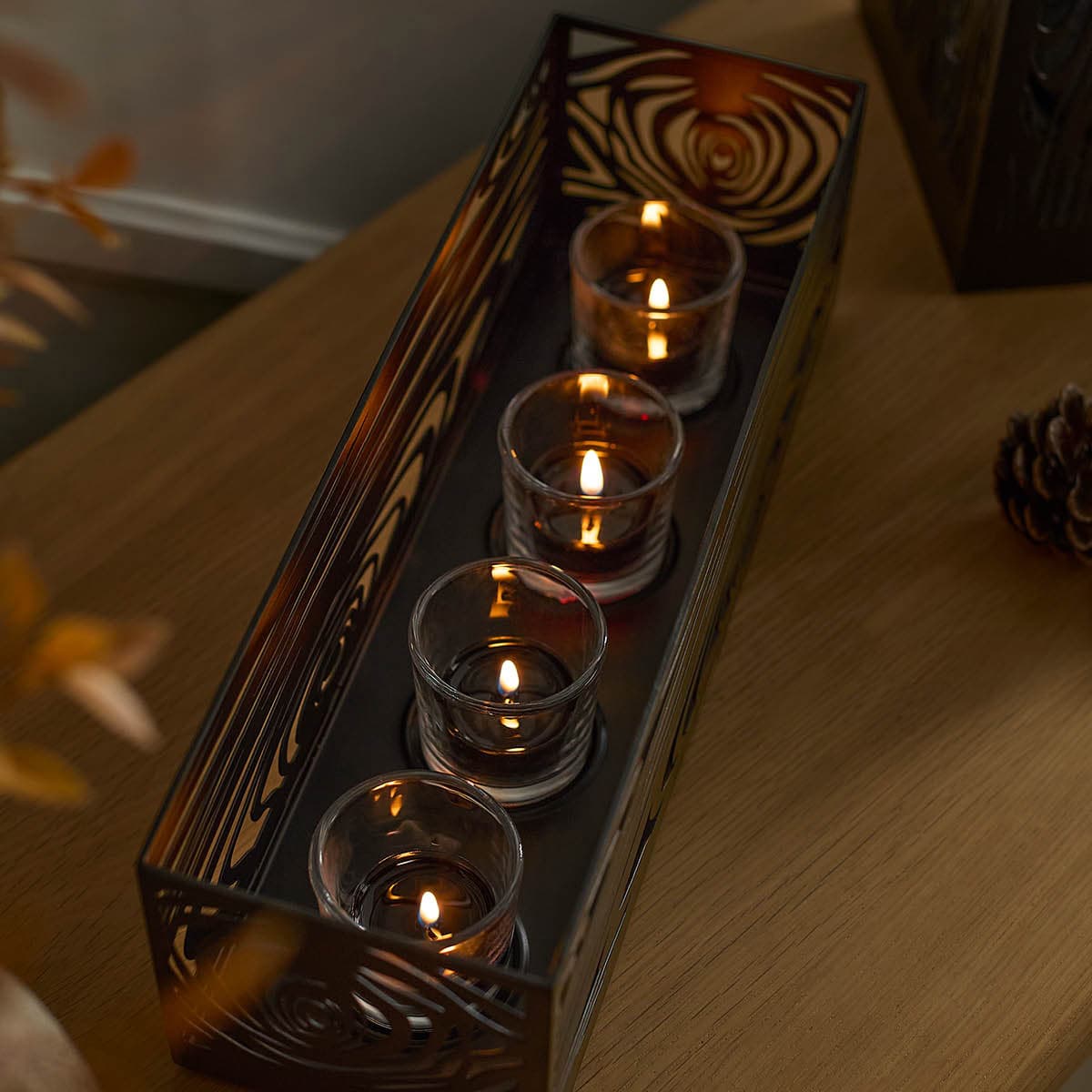 Wood Grain Centerpiece with votive cups and lit candles on a wooden surface.