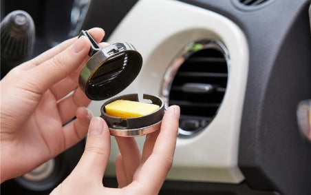Aroma Pure Car air freshener being inserted into a car's air vent.