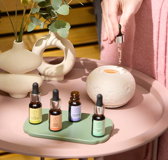 Various Citronella oils shown with a PL oil holder with a vase with flowers on a small table