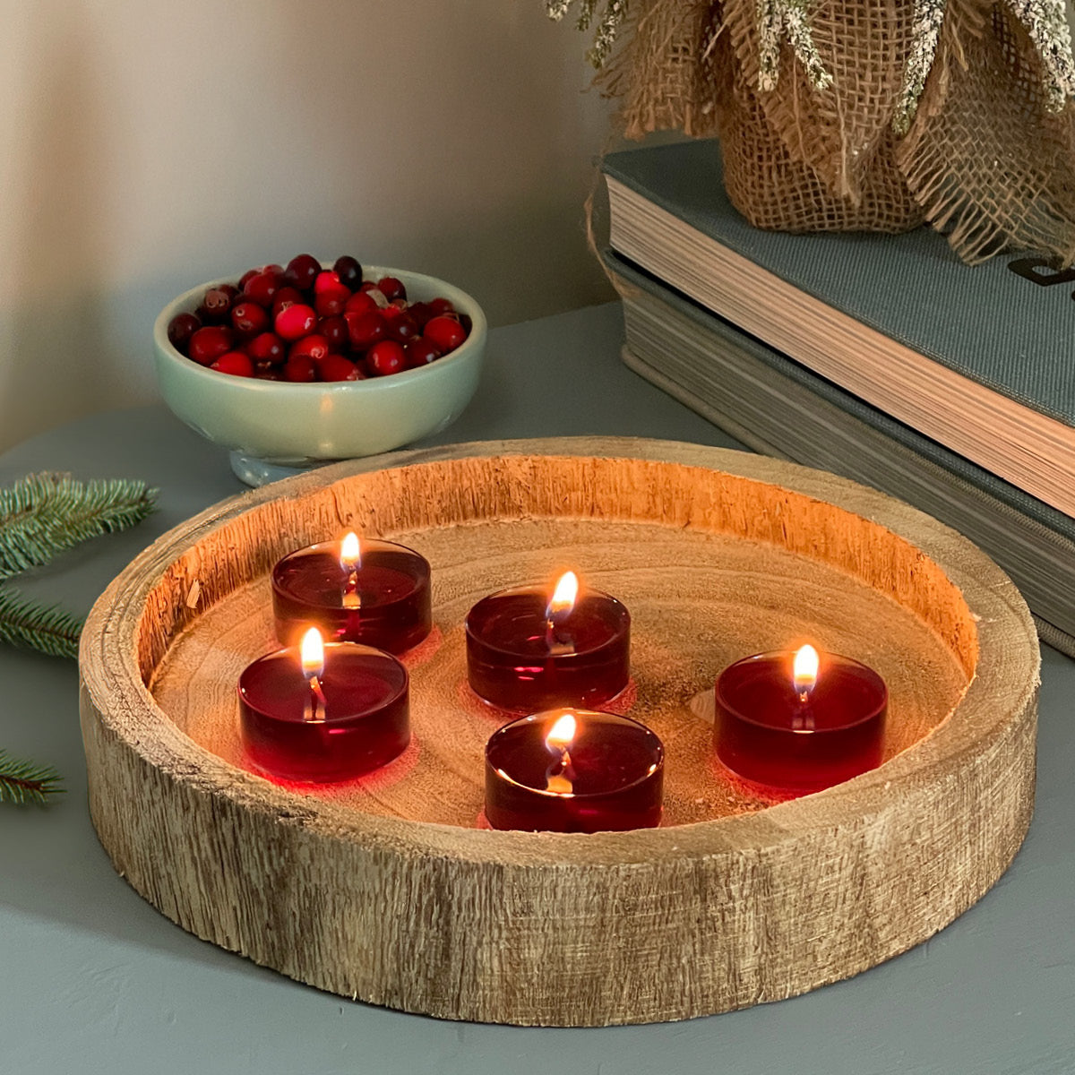 Cranberry Patchouli Bark Tealights on a wooden tray with a bowl of Cherry's in the background and books