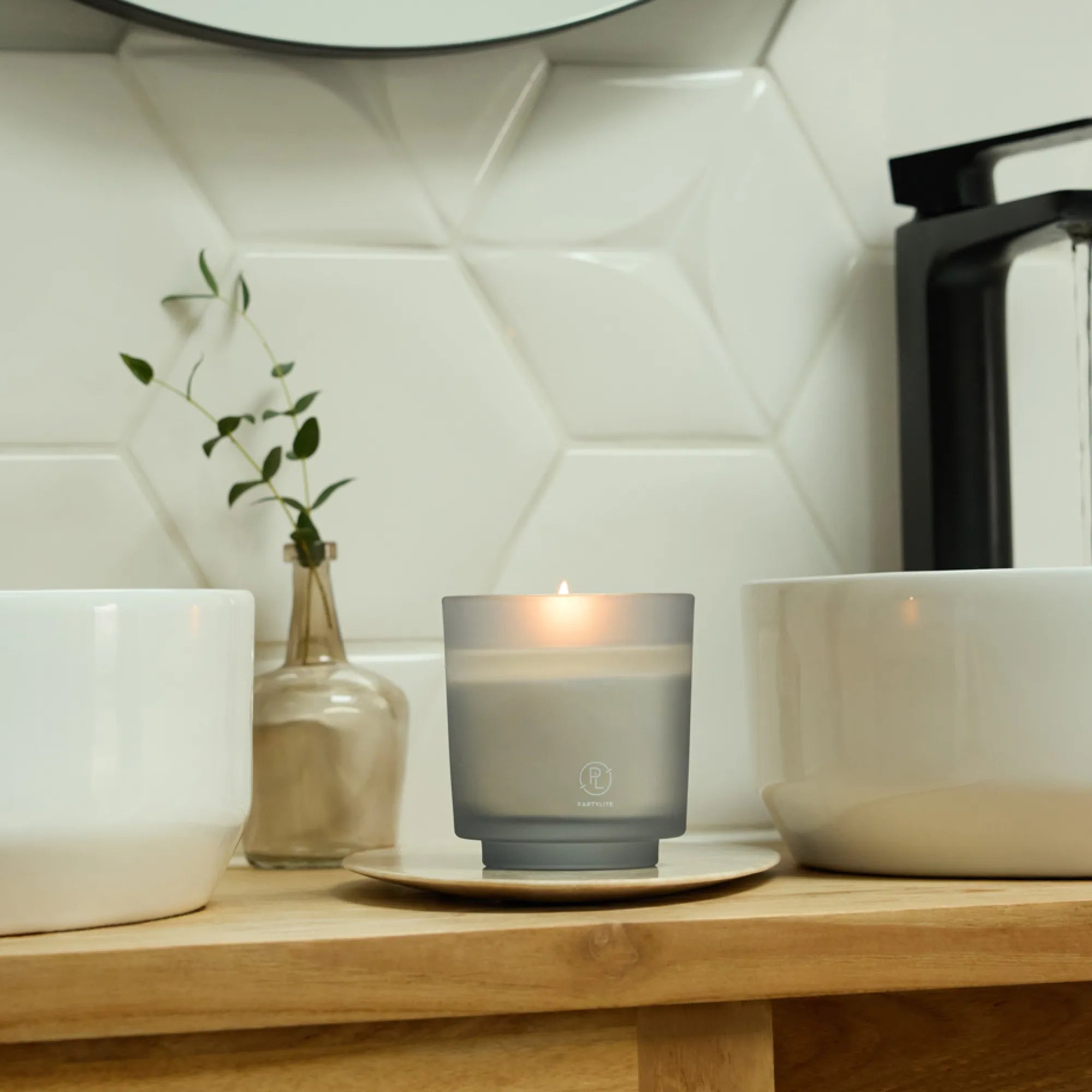 Ocean Lavender Refillable Jar Candle shown with a white sink with a black tap with a white tiled background on a wooden surface and a decoctive clear vase behind the jar candle