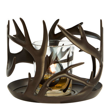 Decorative candle holder with antler design with a lit candle against a white background.