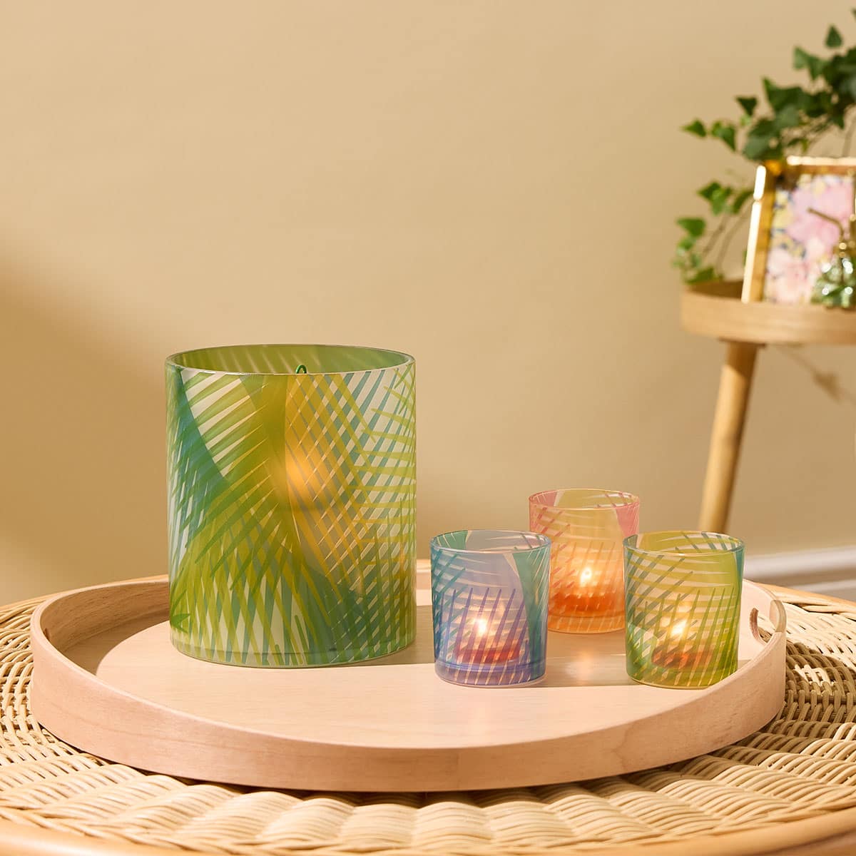 Tropical Palm Tealight/Votive Holder Trio shown with the Tropical Palm Hurricane on a wooden round tray on a woven table mat with a light background