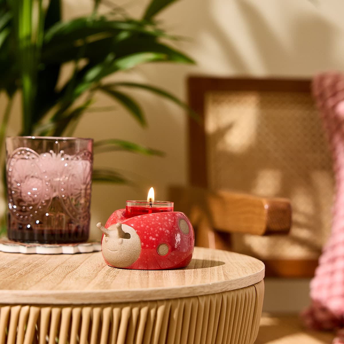 Loveable Ladybug Tealight Holder shown with a light brown transparent glass tealight holder on a wooden table top with a blurred background