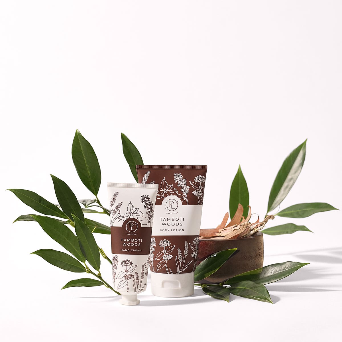 Tamboti Woods Hand Cream & Body Lotion shown with a plant on a white background