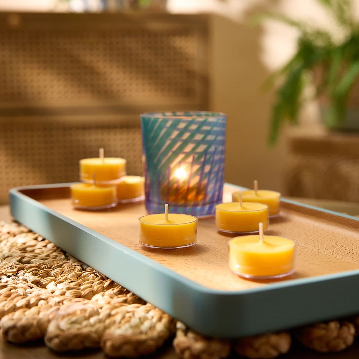 Sun Orchid Pineapple Tealights shown with a Tealight holder on a wooden tray on a woven table mat