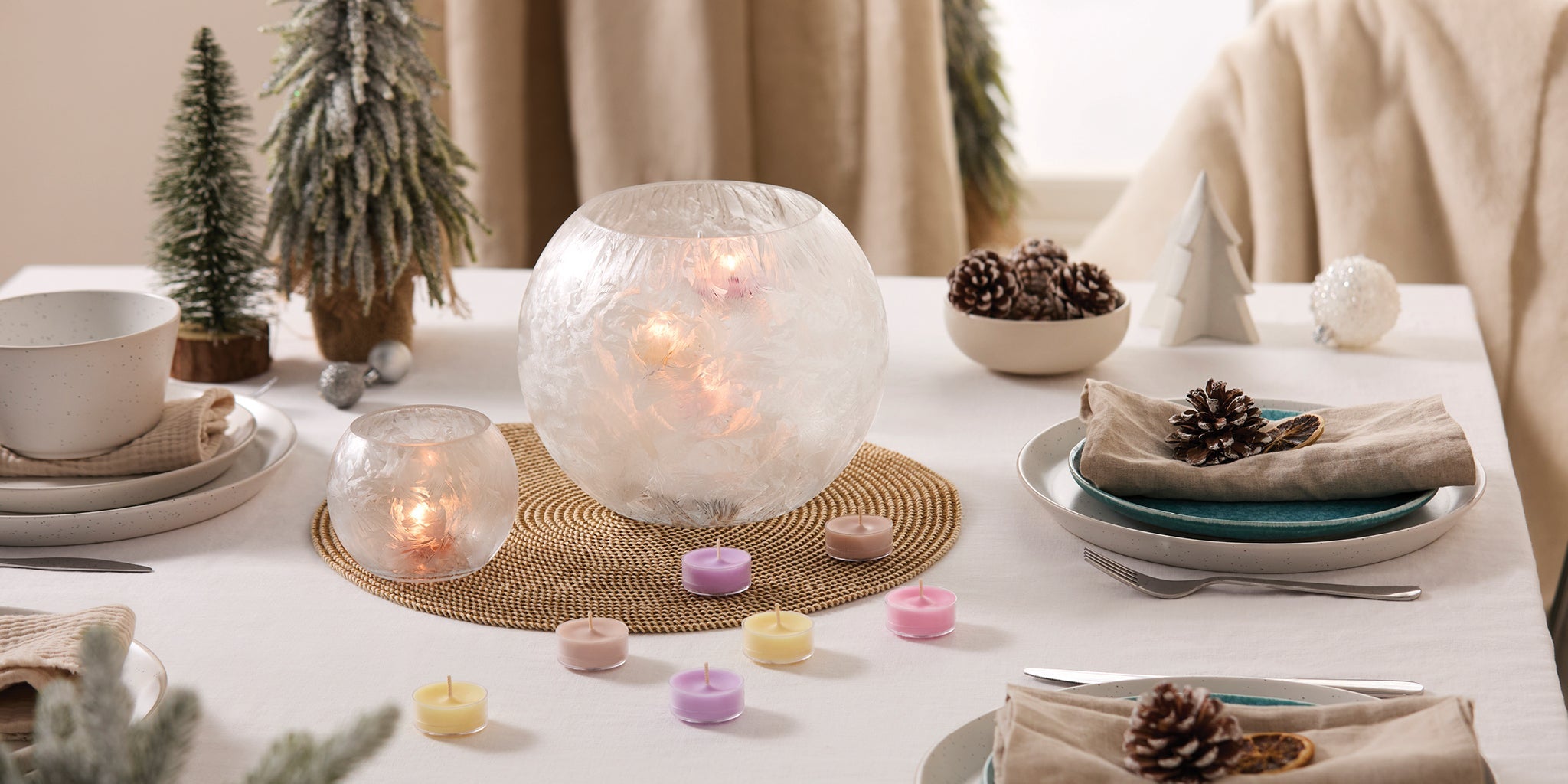 Crystalline Hurricane and Large Tealight Holder on a table with a white tablecloth along with tealights, place settings and pine tree decorations