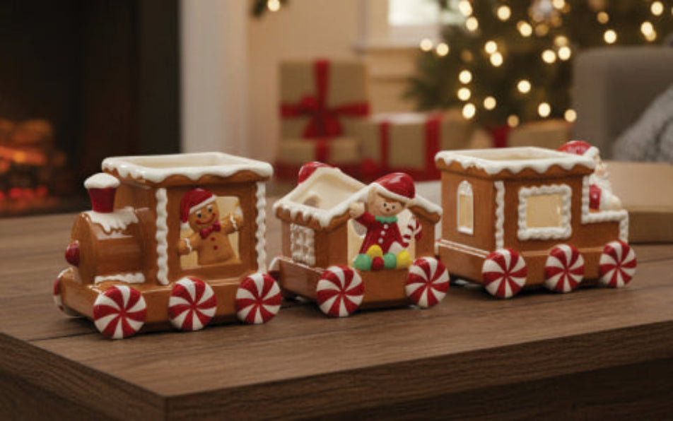 Decorative gingerbread train on a wooden surface with Christmas decorations in the background.