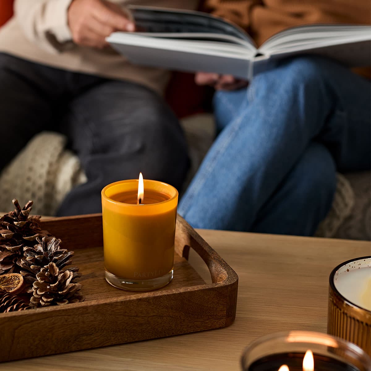 Pistachio Biscotti Escential Jar Candle lit on a wooden tray on a wooden table.