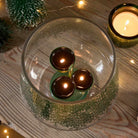 Lacy Greens Hurricane with tealight tree holding 3 lit tealights on a wooden surface.