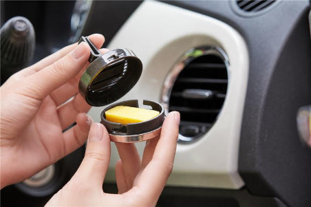 Aroma Pure Car air freshener being inserted into a car's air vent.