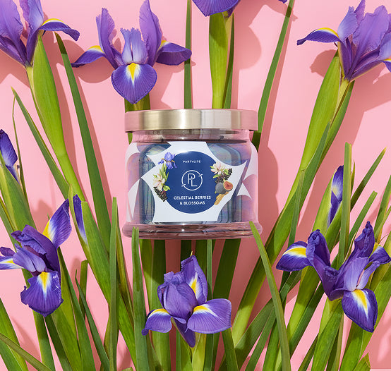 Celestial Berries and Blossoms blue 3-wick jar candle against a pink background with colourful flowers.