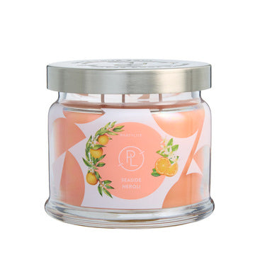 Seaside Neroli fragrance 3-wick jar candle with orange wax and a decorative label with oranges on against a white background.