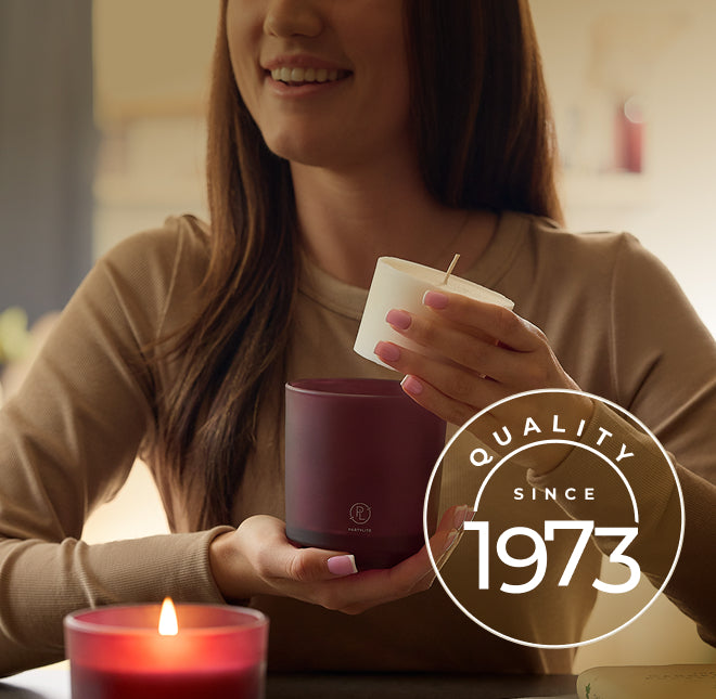 Woman holding a Mulberry candle holder and a white candle refill with 'Quality Since 1973' logo.
