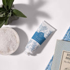 Sea Salt and Sage hand cream on a white surface with decorative bowl of salt and sage leaf's next to it